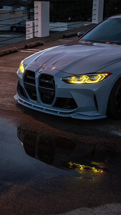 BMW M4 G82 Competion xDrive with lights reflected in puddle